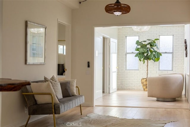 interior space with brick wall, light wood finished floors, and baseboards