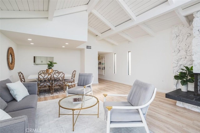 living room with light hardwood / wood-style floors, beam ceiling, high vaulted ceiling, and a high end fireplace