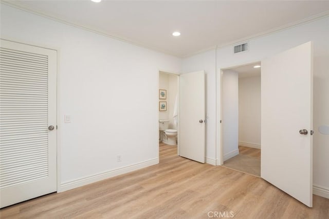 unfurnished bedroom featuring ensuite bath, a closet, light hardwood / wood-style flooring, and crown molding