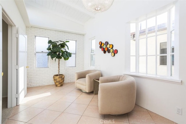 sitting room with brick wall, vaulted ceiling with beams, plenty of natural light, and tile patterned flooring