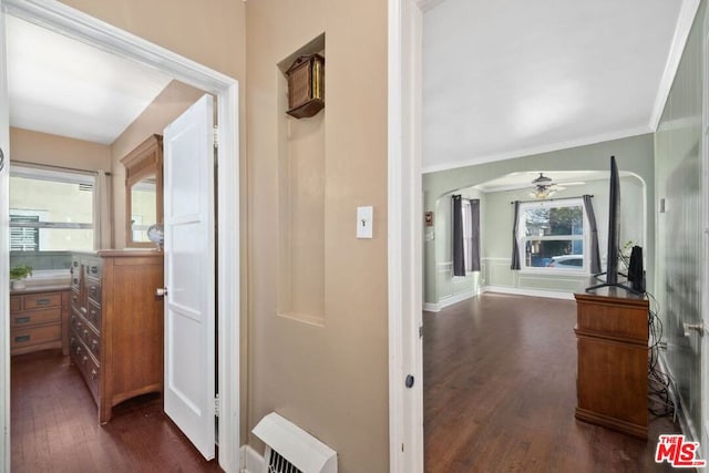 hallway featuring crown molding, dark wood-type flooring, plenty of natural light, and decorative columns