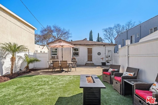 rear view of property with a fire pit, a lawn, and a patio