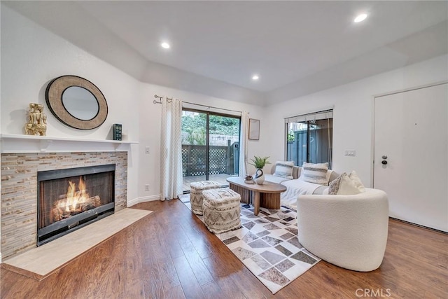 living room with hardwood / wood-style floors and a stone fireplace