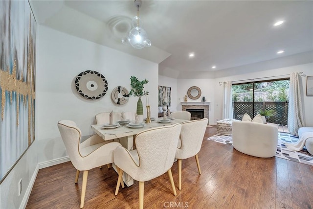 dining area featuring a stone fireplace and dark hardwood / wood-style flooring