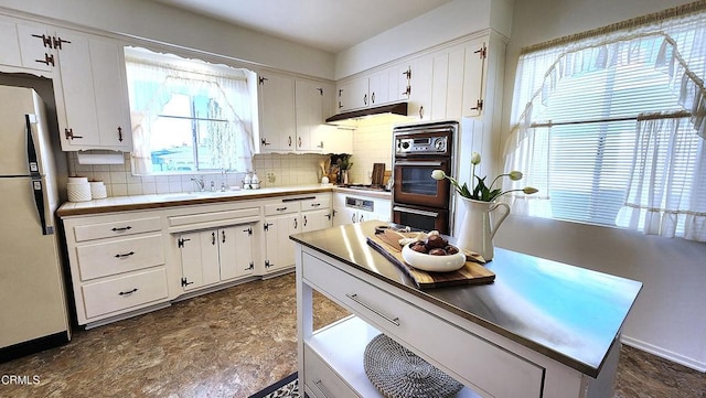 kitchen with white cabinets, a wealth of natural light, white refrigerator, and sink