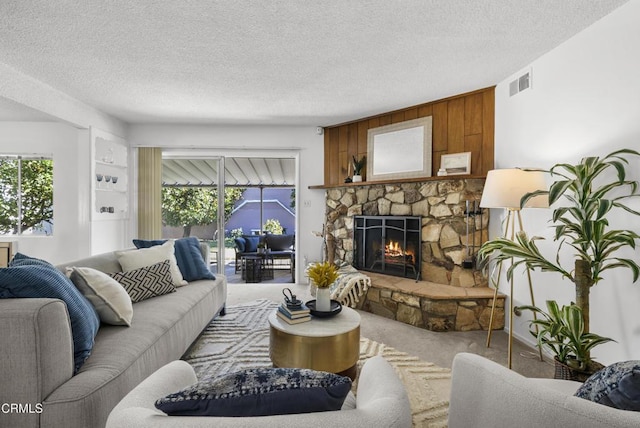 living room with built in features, carpet flooring, a fireplace, and a textured ceiling