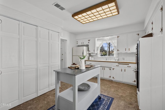 kitchen with decorative backsplash, sink, white cabinets, and white fridge