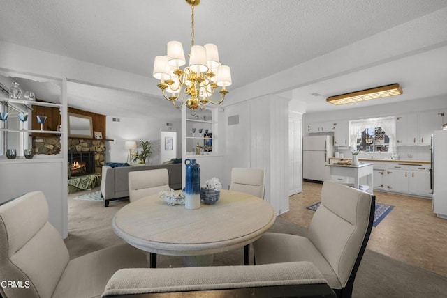 dining space featuring an inviting chandelier and a stone fireplace