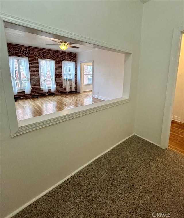 empty room featuring ceiling fan, brick wall, and carpet