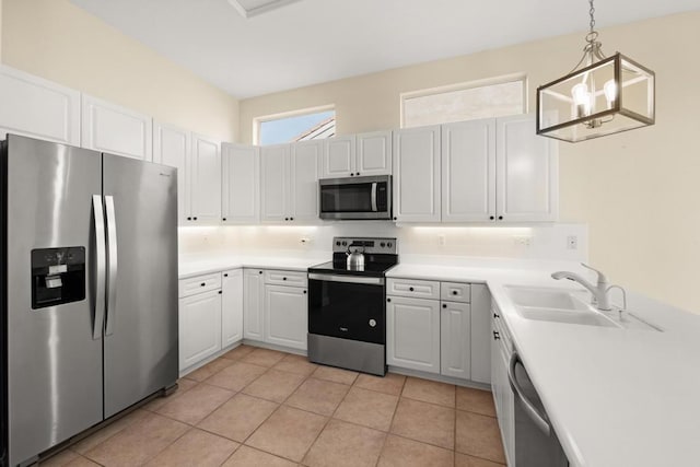 kitchen featuring appliances with stainless steel finishes, white cabinetry, hanging light fixtures, light tile patterned floors, and sink