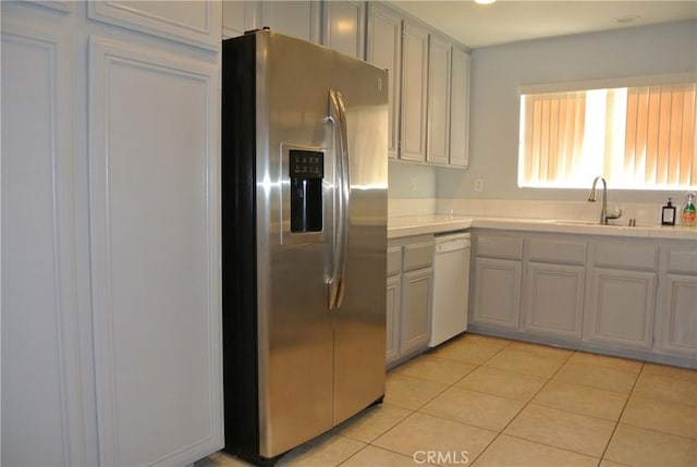 kitchen with sink, gray cabinetry, light tile patterned floors, white dishwasher, and stainless steel refrigerator with ice dispenser