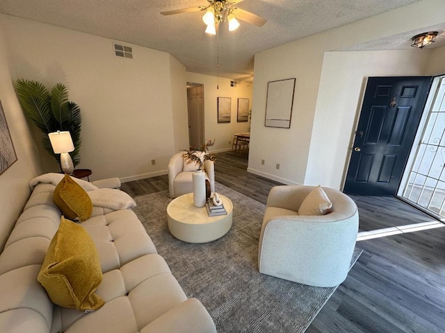 living room with ceiling fan, dark hardwood / wood-style floors, and a textured ceiling