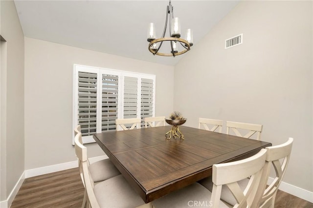 dining room with dark wood-type flooring, a chandelier, and lofted ceiling