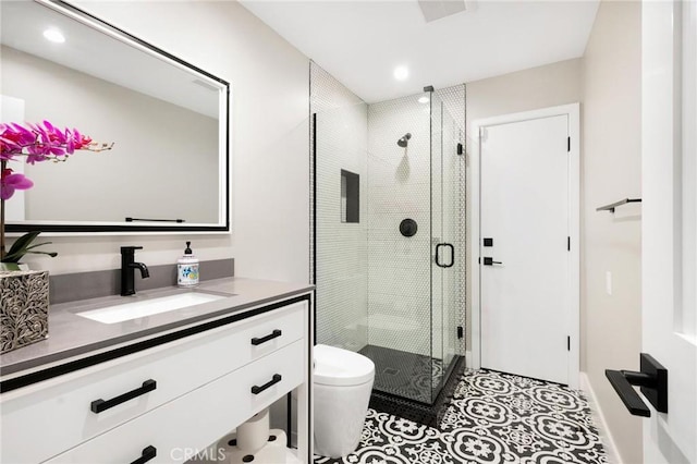 bathroom featuring vanity, a shower with shower door, tile patterned flooring, and toilet