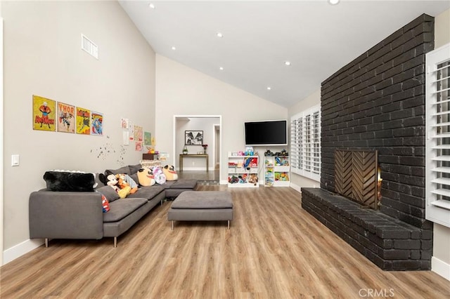 living room with high vaulted ceiling, light hardwood / wood-style flooring, and a fireplace