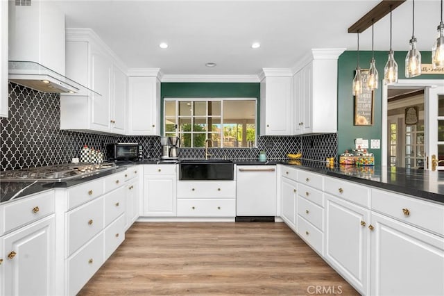 kitchen featuring wall chimney exhaust hood, white cabinets, decorative light fixtures, and dishwasher