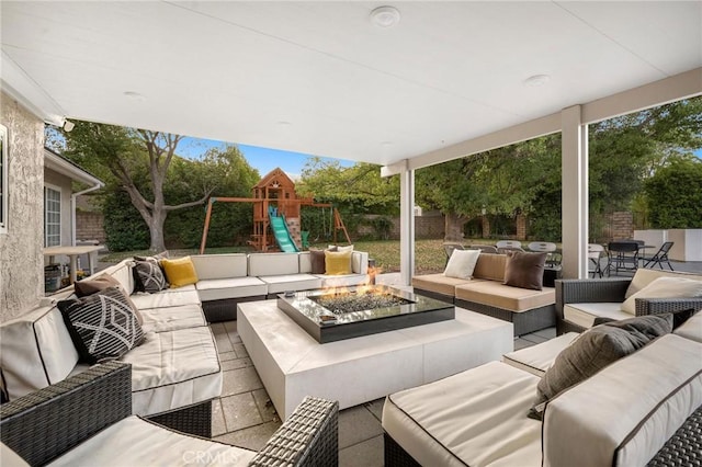 view of patio with a playground and an outdoor living space with a fire pit