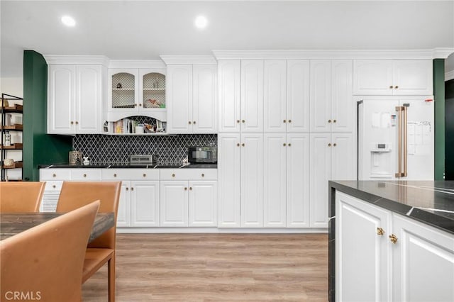 kitchen featuring light hardwood / wood-style floors, white cabinetry, white refrigerator with ice dispenser, and tasteful backsplash