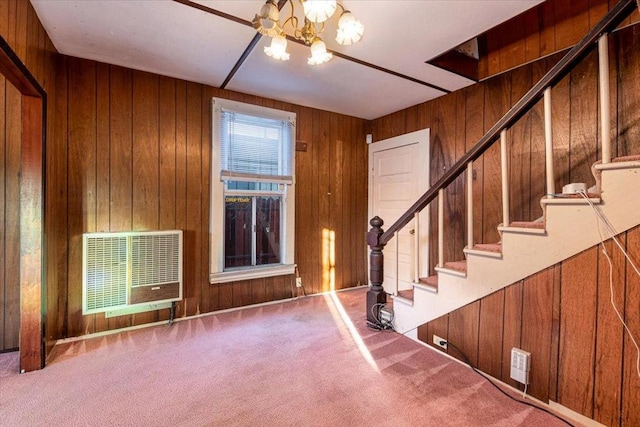 carpeted entrance foyer featuring heating unit, wooden walls, and an inviting chandelier