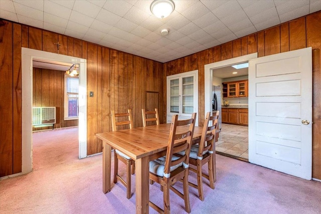 carpeted dining area featuring wood walls