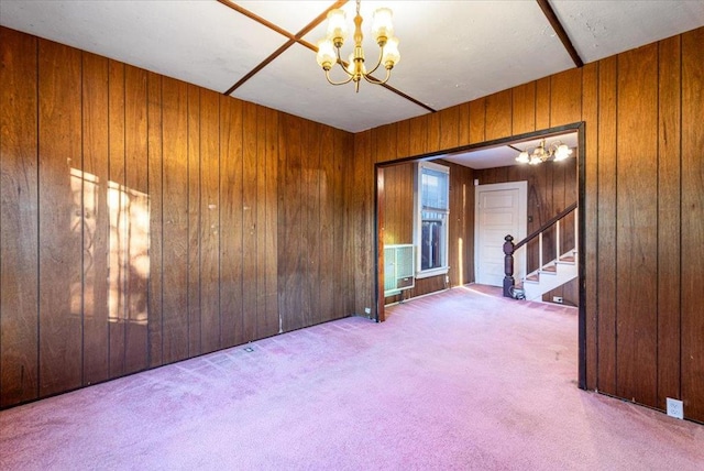 unfurnished room with carpet floors, wooden walls, and an inviting chandelier