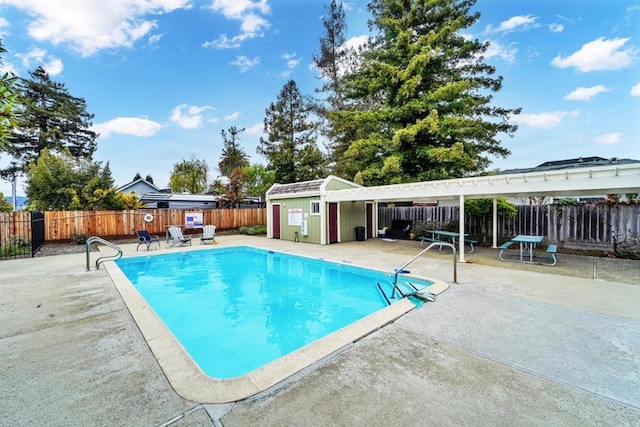 view of pool featuring a patio and a shed