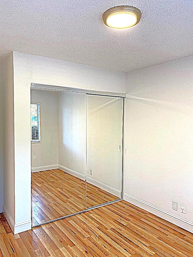 unfurnished bedroom featuring a closet, hardwood / wood-style flooring, and a textured ceiling