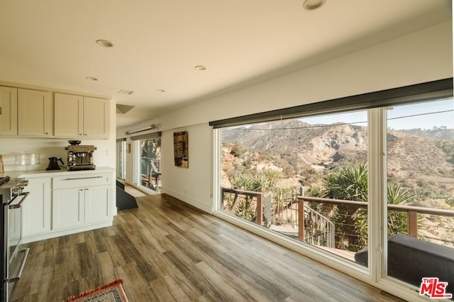 kitchen featuring a mountain view, stainless steel range, white cabinetry, and hardwood / wood-style floors