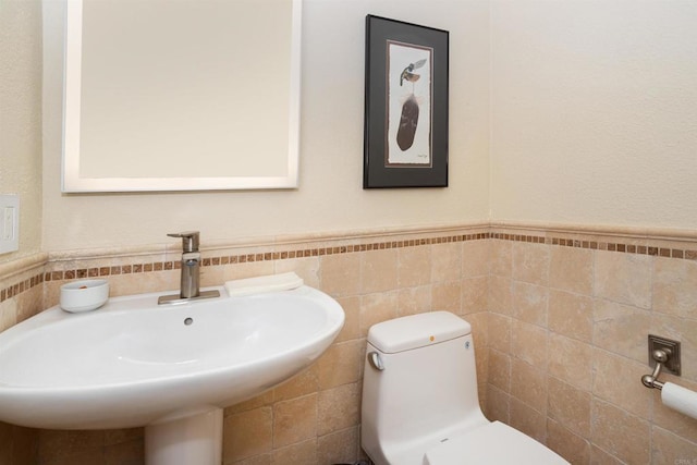 bathroom featuring sink, toilet, and tile walls