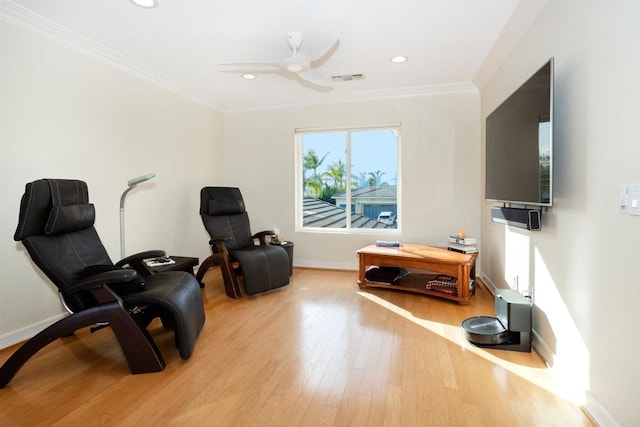 sitting room with light wood-type flooring, ceiling fan, and ornamental molding