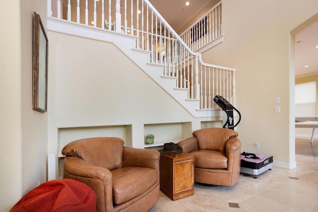 interior space featuring ornamental molding, stairway, light tile patterned floors, baseboards, and a towering ceiling