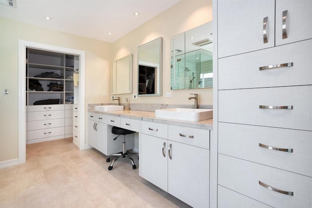 bathroom featuring a spacious closet, recessed lighting, double vanity, and a sink