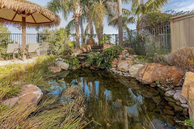 exterior space featuring a garden pond and fence