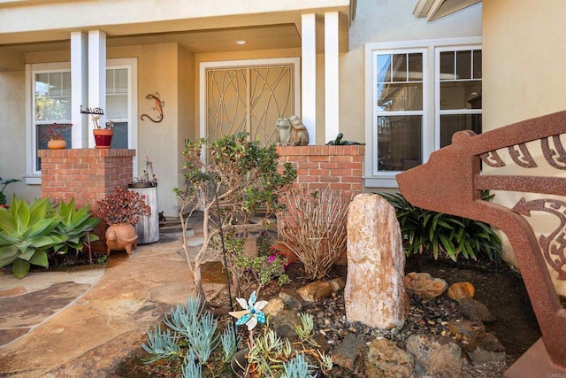 entrance to property featuring stucco siding and brick siding