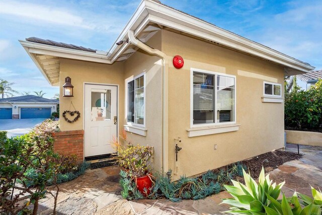 doorway to property featuring stucco siding and brick siding