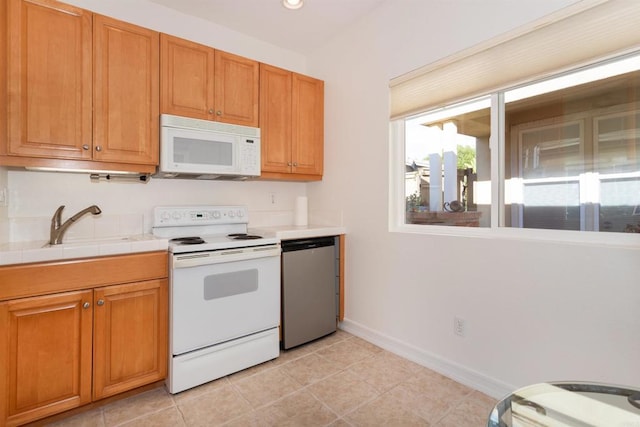 kitchen featuring baseboards, white appliances, brown cabinets, and tile counters