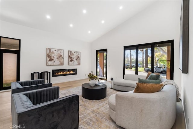 living area with light wood-type flooring, high vaulted ceiling, recessed lighting, and a healthy amount of sunlight
