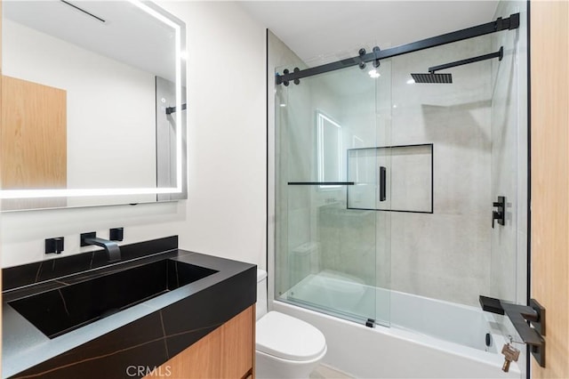 full bath with vanity, toilet, and bath / shower combo with glass door