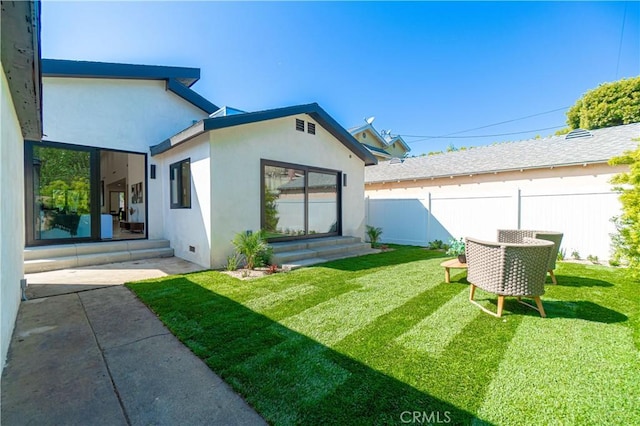 rear view of property featuring stucco siding, a yard, entry steps, and fence