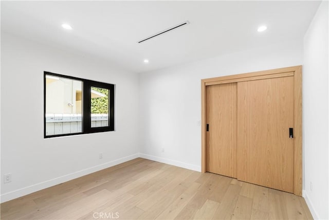 unfurnished bedroom with baseboards, light wood finished floors, and recessed lighting