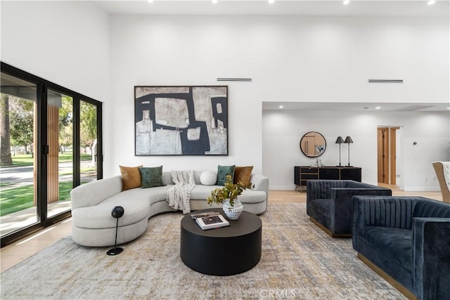 living room featuring recessed lighting, wood finished floors, visible vents, and a towering ceiling