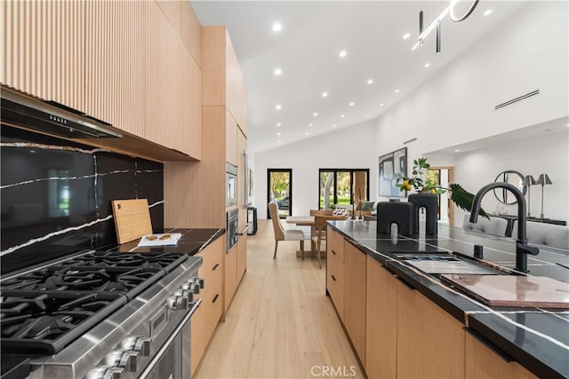 kitchen with modern cabinets, light brown cabinetry, and appliances with stainless steel finishes