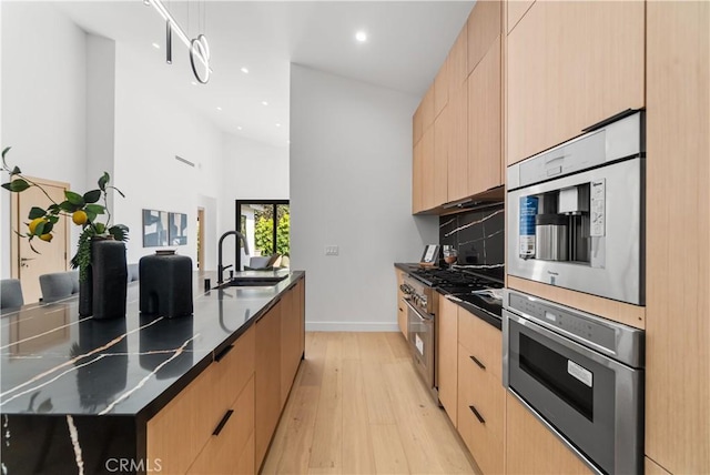 kitchen with recessed lighting, light brown cabinets, modern cabinets, a sink, and light wood-style flooring