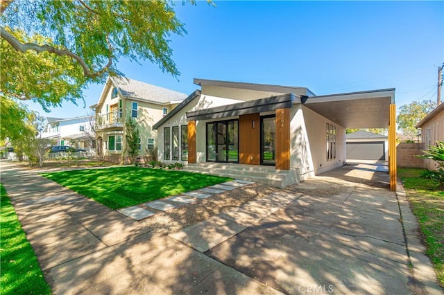 view of front of property featuring a carport, driveway, fence, an outdoor structure, and a front yard