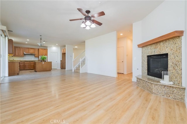 unfurnished living room with light hardwood / wood-style floors, ceiling fan, and a fireplace