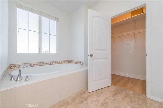 bathroom featuring wood-type flooring and a relaxing tiled tub