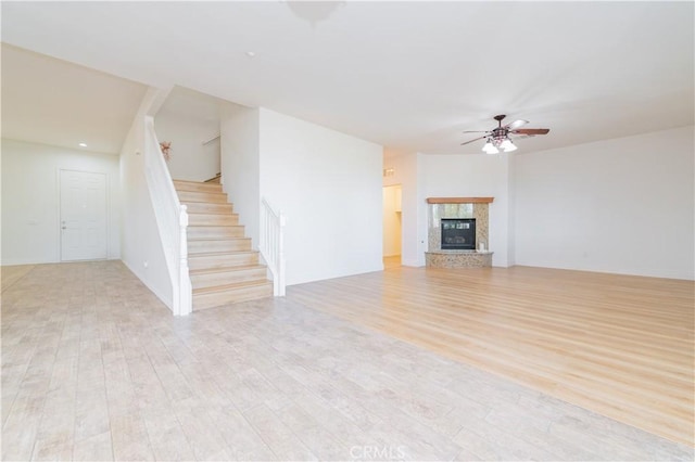 unfurnished living room with ceiling fan, light hardwood / wood-style floors, and a high end fireplace