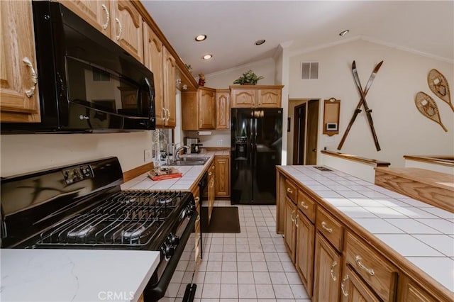 kitchen featuring vaulted ceiling, sink, light tile patterned floors, tile countertops, and black appliances