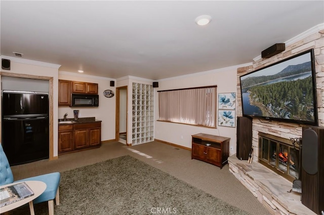 carpeted living room with a fireplace, sink, and crown molding