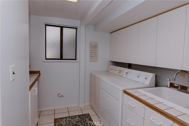 washroom with light tile patterned floors, sink, cabinets, and washer and clothes dryer